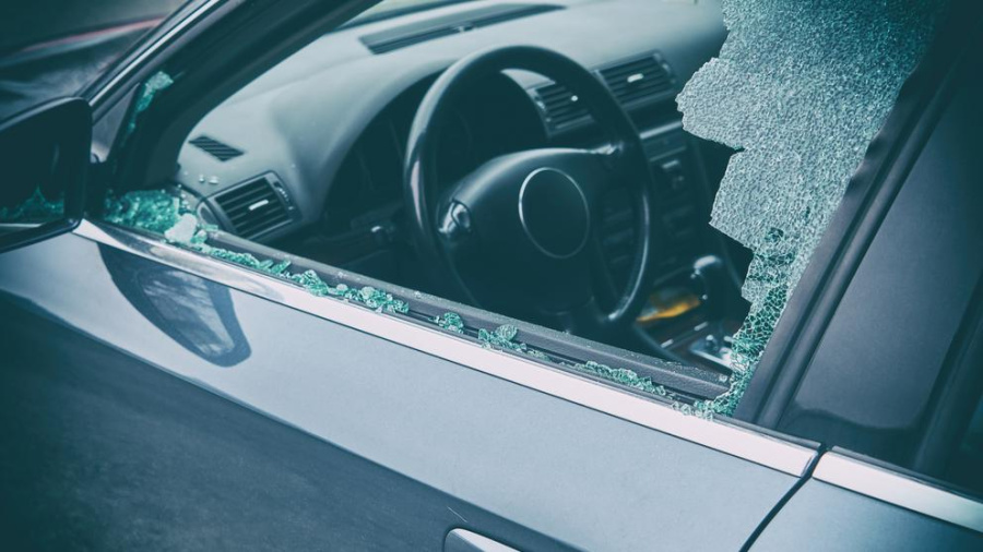 Broken driver's side window of a car due to theft.